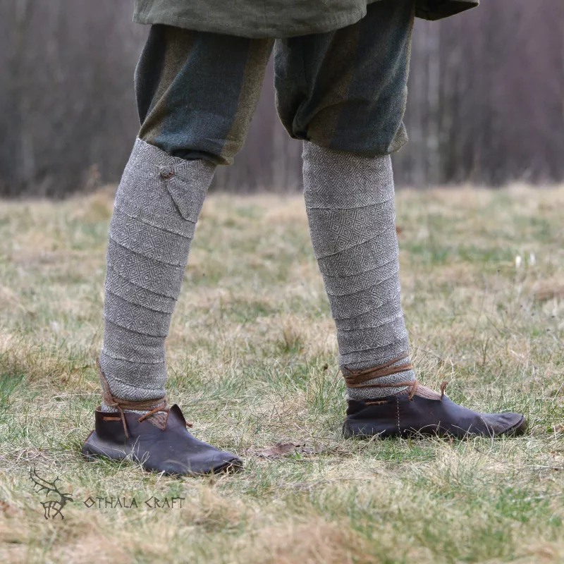 A pair of leg wraps, made from wool in a diamond pattern. Natural shades of sheep's wool were used for the weaving.