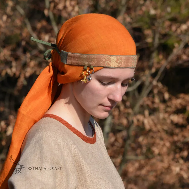 The headband is made of linen in burgundy, decorated with layer woven in a pattern of ancient silk. Earflaps on the sides.