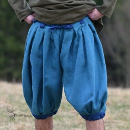 Trousers made of blue plain weave linen. Legs and belt loops made of dark blue linen. Pleated waistband and legs.