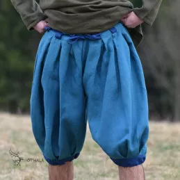 Trousers made of blue plain weave linen. Legs and belt loops made of dark blue linen. Pleated waistband and legs.